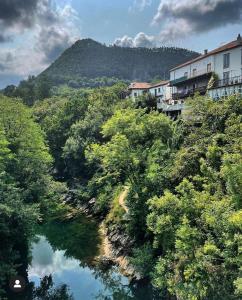 un río con árboles y edificios en una colina en HdeC Hosteria de Castañeda Alojamiento Turistico en Puente Viesgo