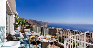 uma varanda com uma mesa e cadeiras e o oceano em Casa Giafari em Taormina