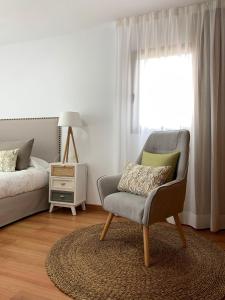 1 dormitorio con silla, cama y ventana en Apartamentos Los Catorce, EL Hierro en Valverde