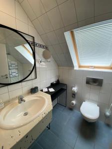 La salle de bains est pourvue d'un lavabo, de toilettes et d'un miroir. dans l'établissement Hotel Restaurant Zur Post, à Odenthal
