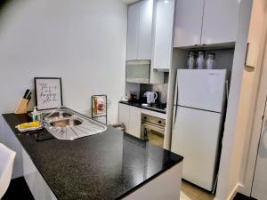 a kitchen with a black counter top and a refrigerator at Collins central 2-bd apartment with pre-reserve parking in Melbourne