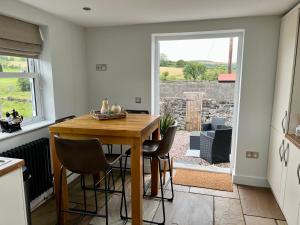 una cucina e una sala da pranzo con tavolo e sedie di Penderyn Cottage Waterfall Country Brecon Beacons ad Aberdare