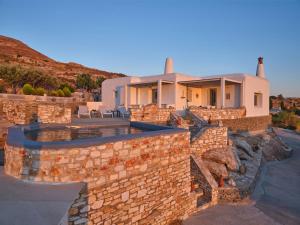 una casa con un muro in pietra e una piscina di VILLA STELLA, LEFKES PAROS a Lefkes