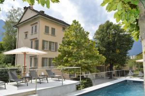 a house with a swimming pool and chairs and an umbrella at VILLA CHIOVENDA Residenza d'Epoca in Premosello Chiovenda
