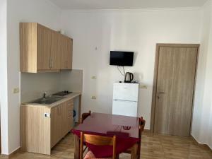 a small kitchen with a table and a refrigerator at Vila Sidi in Ksamil