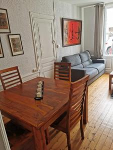 een woonkamer met een houten tafel en een bank bij Appartement de charme in Honfleur