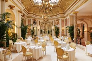 a restaurant with white tables and chairs and a chandelier at The Ritz London in London