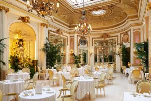 un restaurante con mesas y sillas blancas y una lámpara de araña en The Ritz London, en Londres