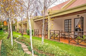 a patio of a house with trees in the yard at Afrique Boutique Hotel O.R. Tambo in Boksburg