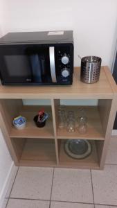 a microwave sitting on top of a wooden shelf at Studio Privé Dijon in Dijon