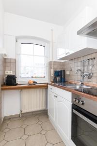 DornumergrodeにあるFerienhaus Hosnhuusの白いキャビネット、シンク、窓付きのキッチン