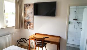 Habitación con escritorio y TV en la pared. en Budget Boarding House Weidenberg, en Weidenberg