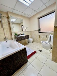 York Backpackers - Jumeirah Beach في دبي: حمام كبير مع حوض استحمام ومرحاض