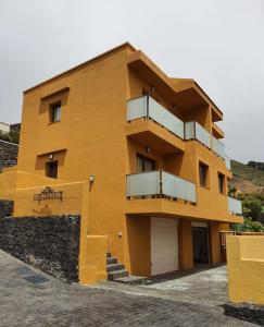 a yellow building with balconies on the side of it at Apartamentos Los Catorce, EL Hierro in Valverde