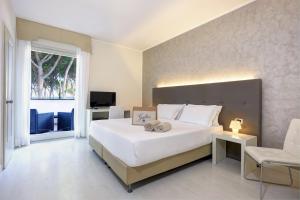 una camera da letto con un grande letto bianco e una finestra di Hotel Gallia & Resort a Lido di Jesolo