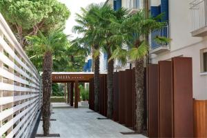 a hallway with palm trees in front of a building at Hotel Gallia & Resort in Lido di Jesolo