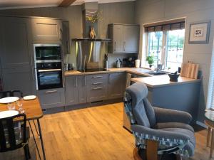 uma cozinha com armários cinzentos, uma mesa e cadeiras em The Floating Home at Upton em Upton upon Severn