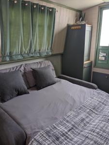 a large bed in a room with a window at Mini Escape - 2 Berth Narrowboat on the Grand Union, Hertfordshire 