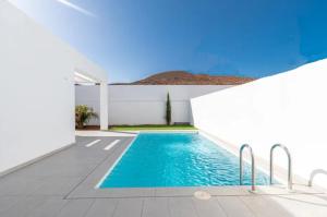 a swimming pool in a house with a white wall at Idaira Suites adosado con piscina a estrenar-WiFi in Palm-mar
