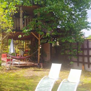 two chairs and a hammock in front of a house at CABANE CERISE DANS L'ARBRE Etapeboisee in Fumay