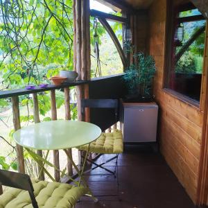 a room with a table and chairs on a balcony at CABANE CERISE DANS L'ARBRE Etapeboisee in Fumay