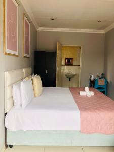 een slaapkamer met een groot wit bed en een roze deken bij Innoview Lodge in Mthatha