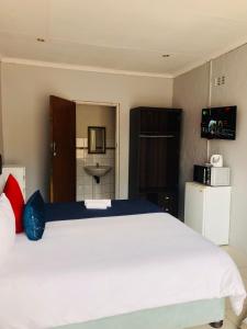 a bedroom with a large white bed and a refrigerator at Innoview Lodge in Mthatha