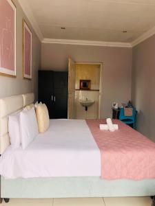 um quarto com uma grande cama branca e um cobertor rosa em Innoview Lodge em Mthatha