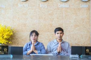 Um homem e uma mulher sentados à mesa com as mãos à frente. em Junlan Hotel em Sihanoukville