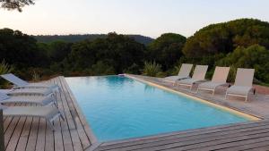 een zwembad met ligstoelen naast een houten terras bij Appartement de 3 chambres avec piscine partagee jardin clos et wifi a Porto Vecchio a 1 km de la plageB in Porto-Vecchio