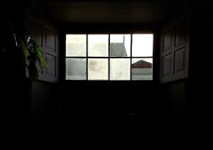 - une fenêtre dans une chambre sombre avec vue sur un bâtiment dans l'établissement Casa de las Flores - Hotel Boutique Lanzarote, à Teguise