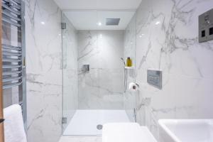 a white bathroom with a shower and a sink at No1 Apartments Edinburgh - New Town in Edinburgh