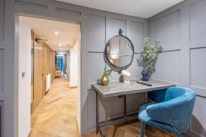 a bathroom with a vanity with a mirror and a blue chair at No1 Apartments Edinburgh - New Town in Edinburgh
