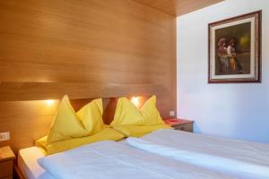 um quarto com uma cama branca e almofadas amarelas em Cesa Soramurat Appartamento 9 em Canazei