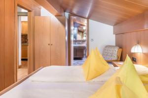 a bedroom with a large white bed with yellow pillows at Cesa Soramurat Appartamento 8 in Canazei +13 photos