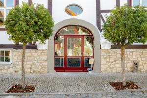 two trees in front of a building with a red door at Hotel & Restaurant Brauner Hirsch Osterwieck in Osterwieck