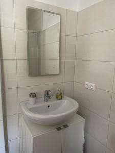 a white bathroom with a sink and a mirror at Ferienwohnungen Berg & See in Döbriach