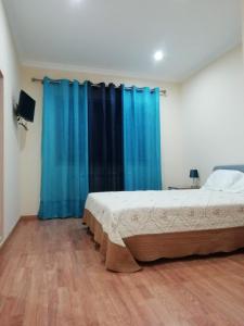 a bedroom with a bed and a blue curtain at Casa da Fonte em Prada, Vinhais in Vinhais