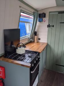 a kitchen with a stove with a tea kettle on it at Mini Escape - 2 Berth Narrowboat on the Grand Union, Hertfordshire 