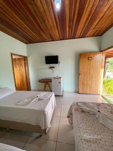 a bedroom with two beds and a tv on the wall at Pousada do Nondas in Nobres