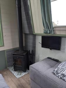 a room with a stove with a bed and a tv at Mini Escape - 2 Berth Narrowboat on the Grand Union, Hertfordshire 