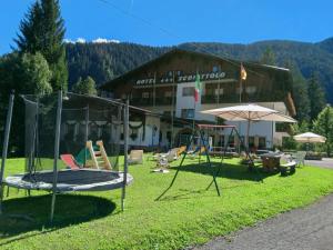 un gruppo di attrezzature per il parco giochi di fronte a un edificio di Albergo Scoiattolo a Falcade