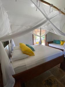 a bed with yellow pillows on it in a room at Pousada Fortal Preá in Prea +164 photos