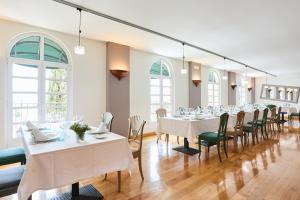 un comedor con mesas y sillas blancas y ventanas en Hotel Silken Villa de Laguardia, en Laguardia