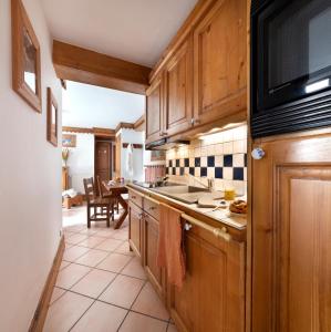 a kitchen with wooden cabinets and a counter top at Résidence Pierre & Vacances Premium La Ginabelle in Chamonix