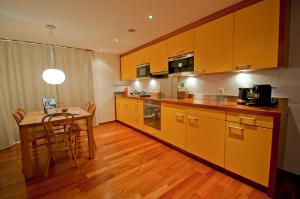 eine Küche mit gelben Schränken und einem Tisch mit Stühlen in der Unterkunft Casa D'Amore, Apartment Lyskamm in Zermatt