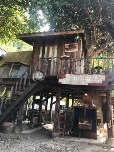 una casa en el árbol con una escalera en el medio en KhonThao, en Lamphun
