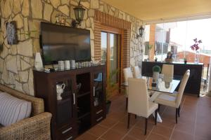 een woonkamer met een televisie en een tafel met stoelen bij chalet relax luxury in Navas del Rey