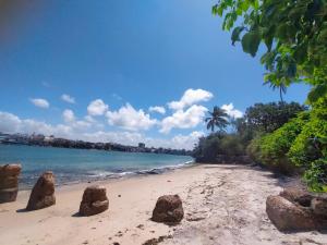 a beach with rocks in the sand and the ocean at CDH Backpackers in Mombasa