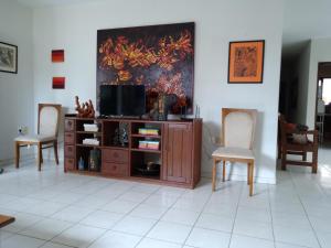 - un salon avec une télévision et deux chaises dans l'établissement Casa super arejada no melhor de Miramar, à João Pessoa